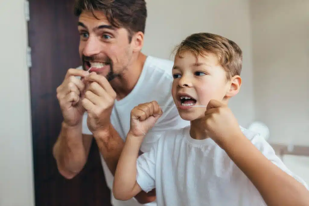 Father and son practicing home teeth cleaning with dental floss