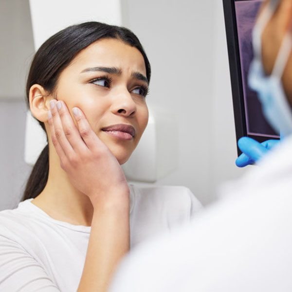 Toothache, dentist and woman in pain, clinic and consultation for dental health of patient in office. Appointment, person and listening to diagnosis of doctor, cavity and medical help for mouth Front Desk