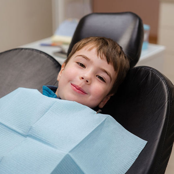 A cute little boy in a dental chair treats his teeth, smiling an Patient Exam
