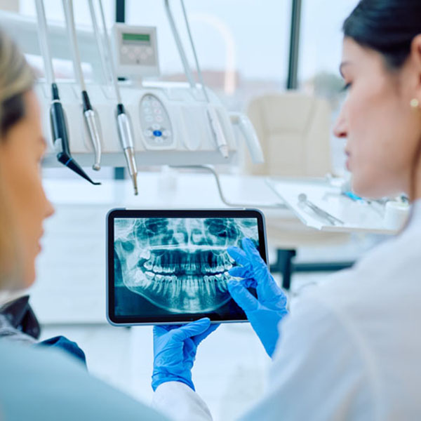 Dentist in blue gloves showing patient panoramic dental x-ray on digital tablet, discussing teeth health in modern office Dr Eberhardt with patient