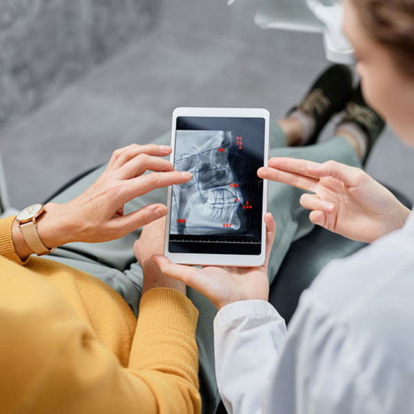 Closeup of dentist holding tablet with X ray images Hallway